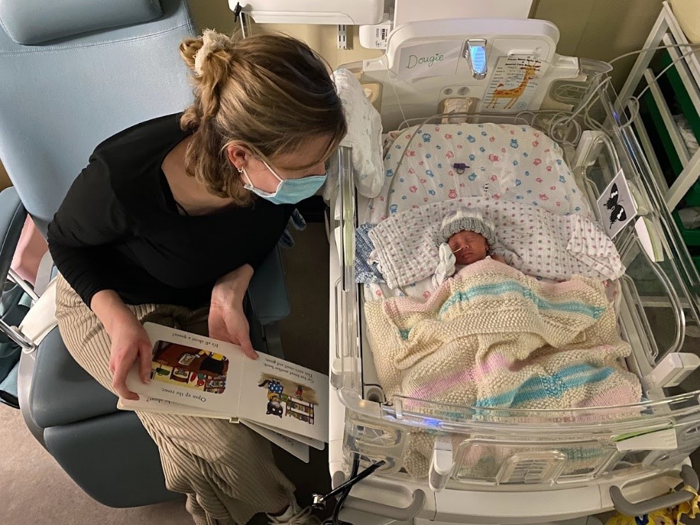 Reading to a baby in an incubator