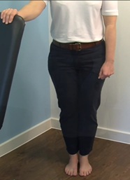 standing with one hand on chair for support