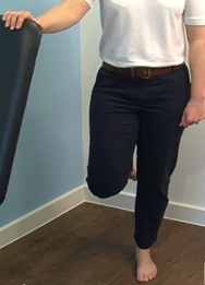 standing with one hand on chair for support on one foot