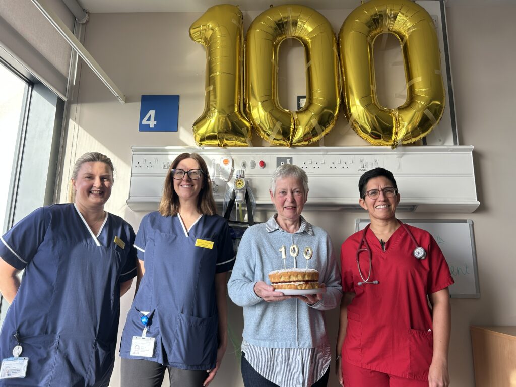 asthma team and 100th patient holding cake