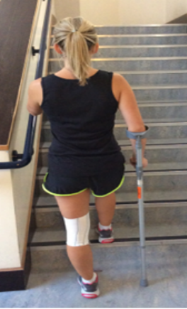 Person going up the stairs holding a crutch