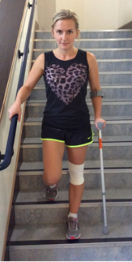 Person going down the stairs holding a crutch