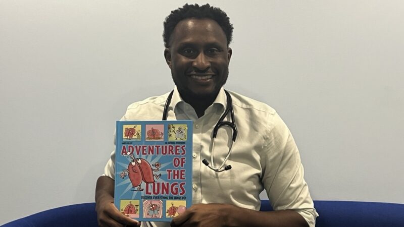 Dr Numbere holding his children's book
