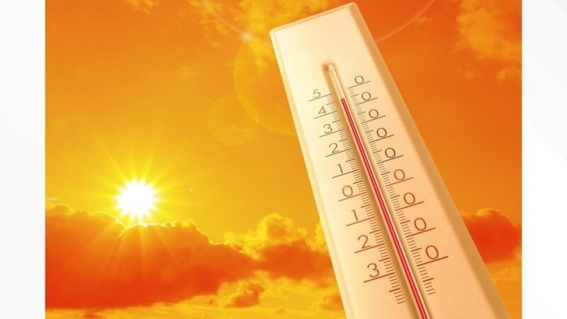 Thermometer showing high temperature against orange backdrop with sun