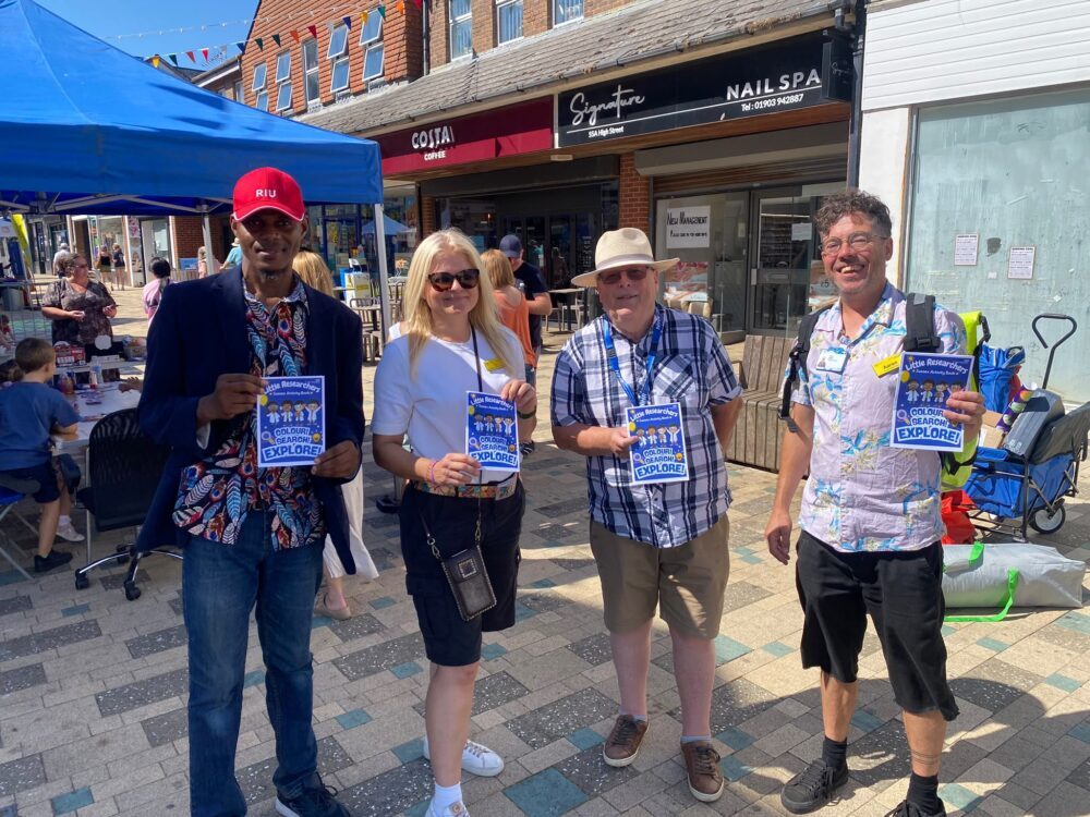Four people holding flyers at a community event.