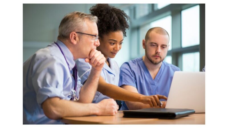 Three staff members looking at a laptop screen