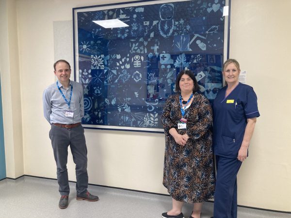 Image of David Grantham (Chief People Officer), Kelly Slater (Health, Wellbeing & Engagement Manager), and Sue Shepherd (Medical Matron) at the tapestry unveiling at Worthing Hospital.